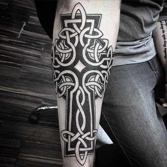 Tribal Celtic Cross Negative Space Guys Tattoo On Forearm