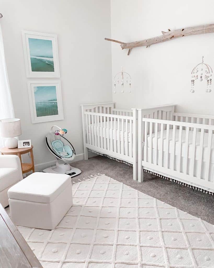 white twins nursery two white cribs framed ocean images white lounge chair and footrest 