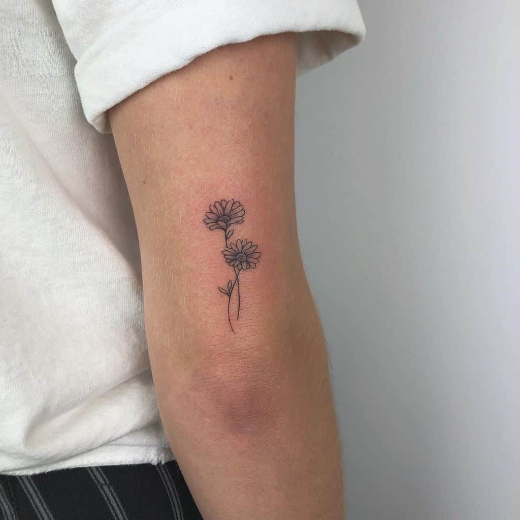 Tricep tattoo two tiny black and grey daisies