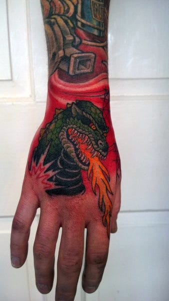 Vibrant Godzilla Spitting Fire Tattoo On Mans Hand