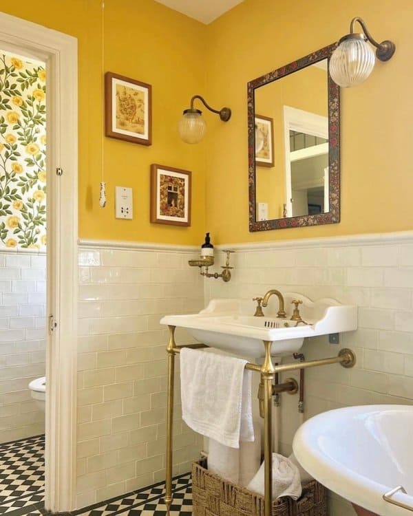 Bathroom featuring bright yellow walls, white subway tile wainscoting, vintage brass fixtures, and floral artwork.