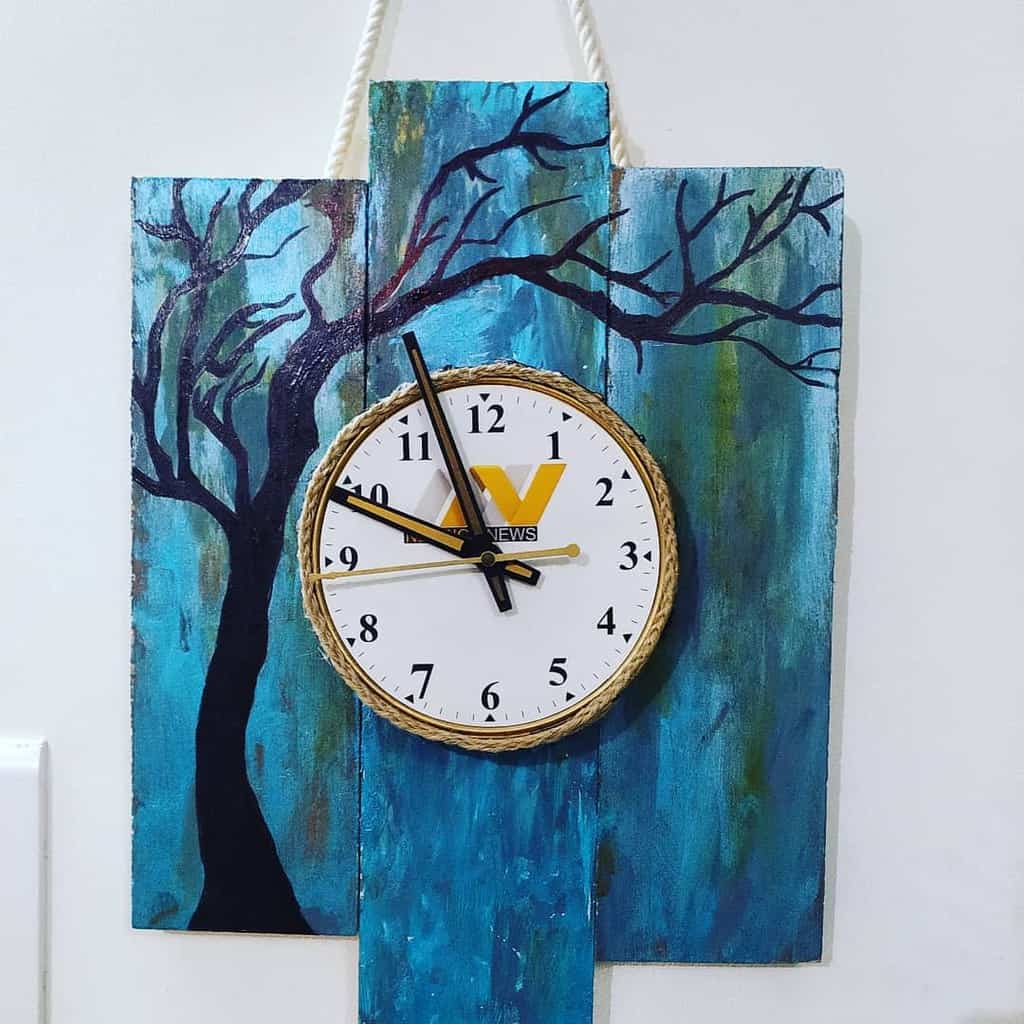 clock on blue wood planks with tree artwork 