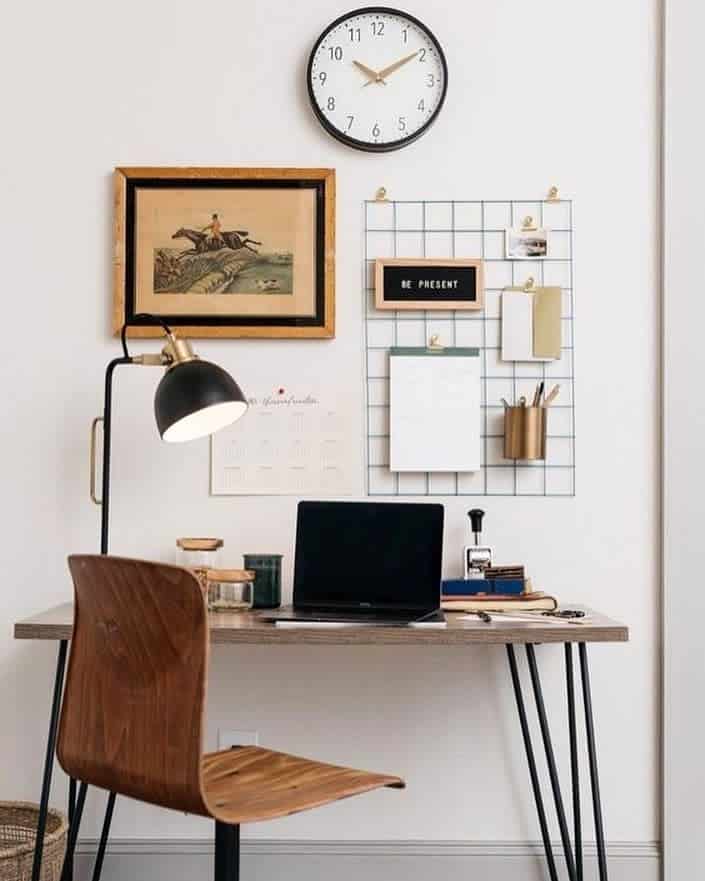 small office space with framed wall art clock and hanging metal grid 