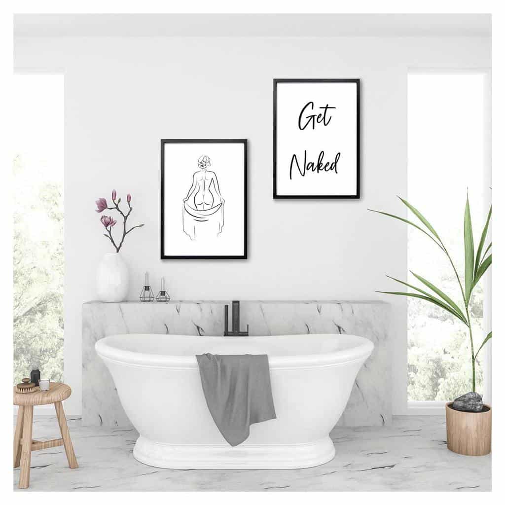 marble bathroom with white freestanding tub and framed wall art