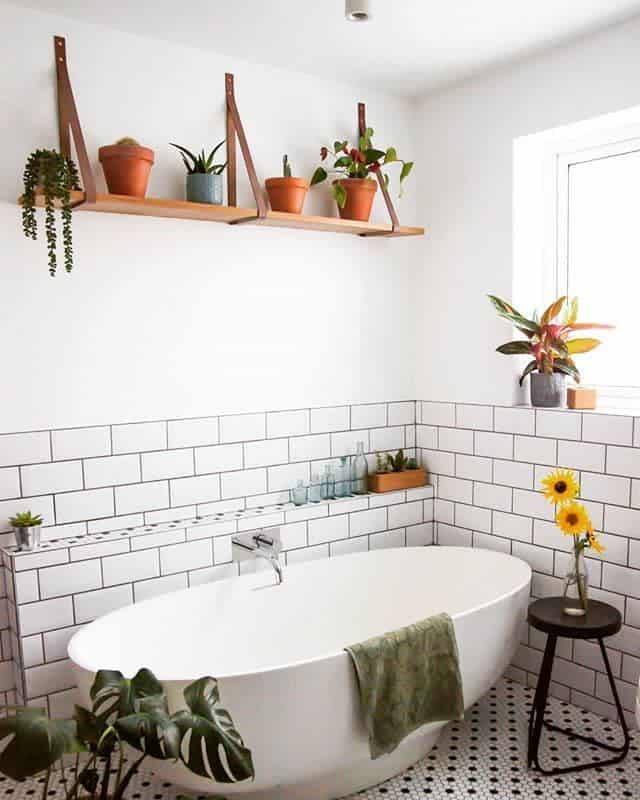 white tile bathroom freestanding tub wood wall shelf with pot plants 