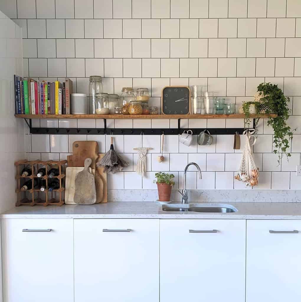 white tile kitchen wall wood shelf with clock glasses and cookbooks 