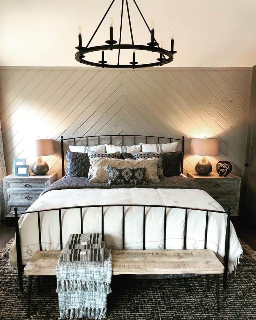 gray shiplap accent wall cast iron bed chandelier wood bench 