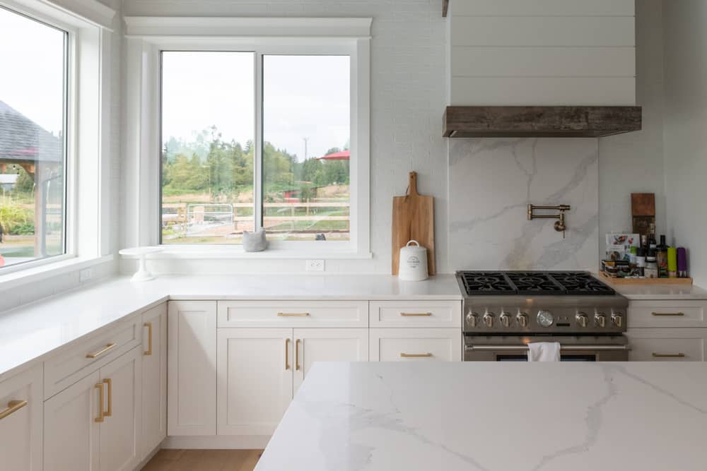 white farmhouse kitchen gold accents white marble spalshback 