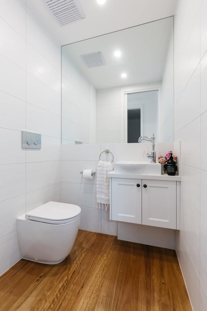 all-white powder room with wood flooring 