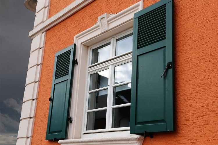 white stucco exterior window trim with green shutters orange wall