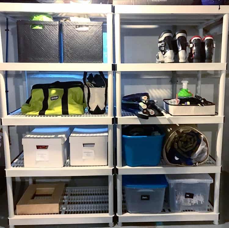 White vertical shelves with organized storage bins, sports gear, and boots in a basement.