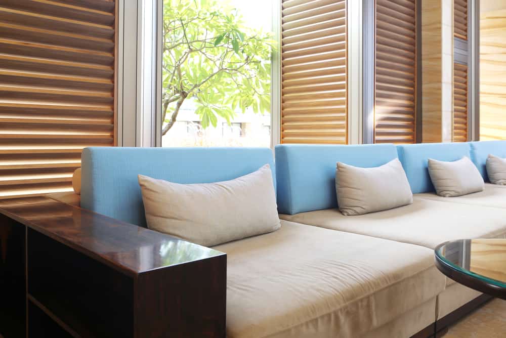 large window shutters long couch with blue pillows 
