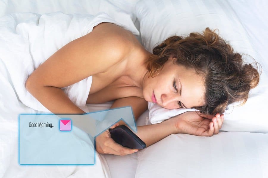 woman lying in bed reading morning texts