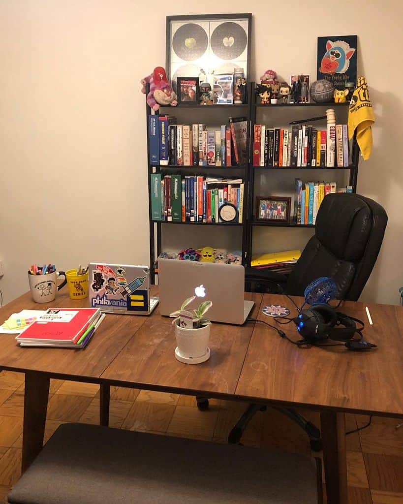 simple wood desk black shelving unit with books and figures 